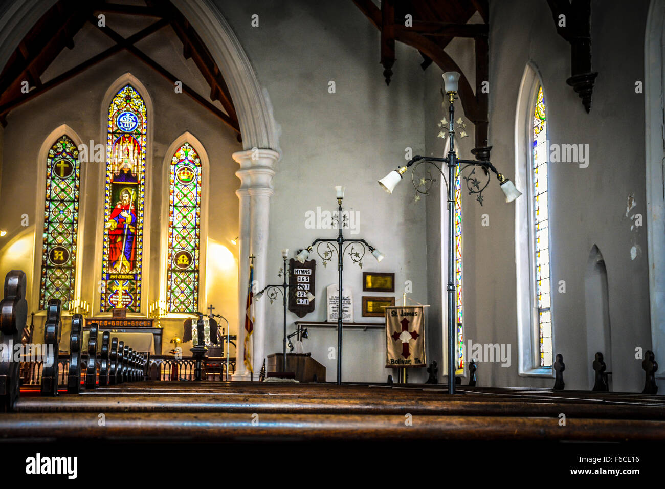 Une sombre et vide intérieur d'une vieille petite église protestante avec bancs en bois décoratif, chaire et vitraux de charme Banque D'Images