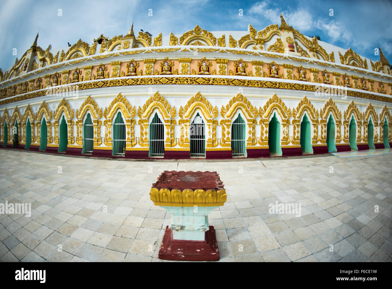 SAGAING, Myanmar — debout sur une colline à Sagaing, la pagode OoHminThoneSel présente une longue alcôve incurvée bordée de dizaines de statues du Bouddha. Après de récentes rénovations et améliorations en cours rendues possibles par des donateurs, la pagode est richement décorée avec des mosaïques de carreaux colorés et de la peinture fraîche et brillante. Banque D'Images