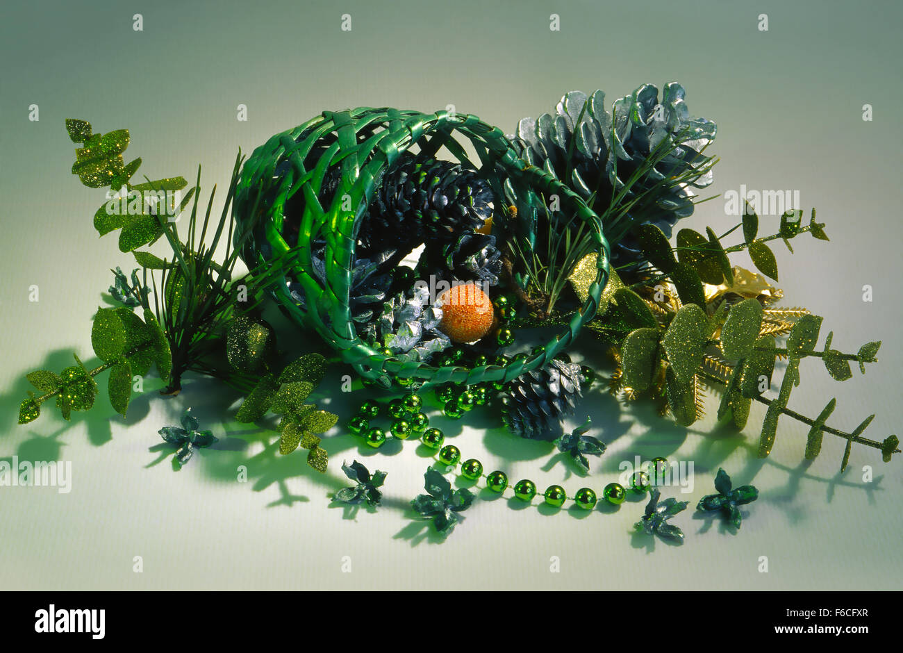 La nouvelle année de fête, Noël encore la vie avec cônes dorés et plantes artificielles dans un panier vert sur un fond clair. Banque D'Images