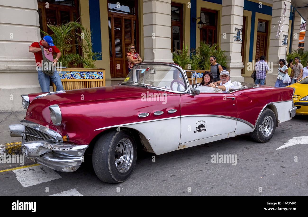 Deux touristes assis dans une vieille décapotable en attente d'une visite dans le vieux Havane, vieille voiture, voiture vintage rouge Banque D'Images