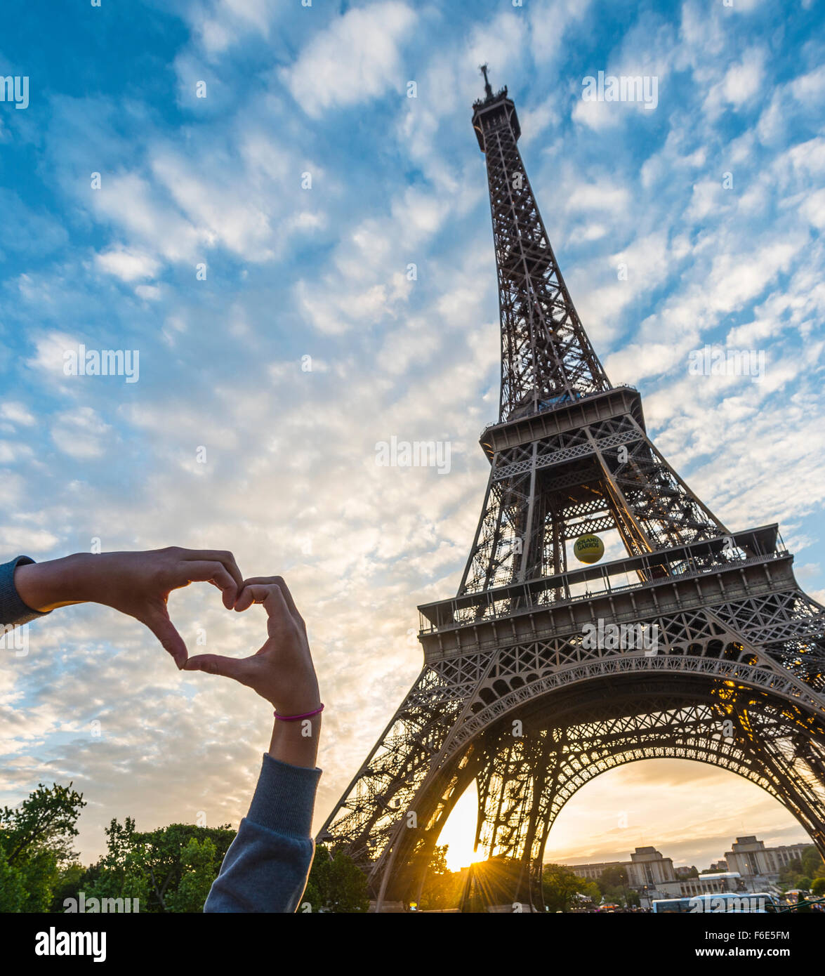 Mains formant le coeur, coucher de soleil derrière la tour Eiffel, du Champ de Mars, Paris, Ile-de-France, France Banque D'Images