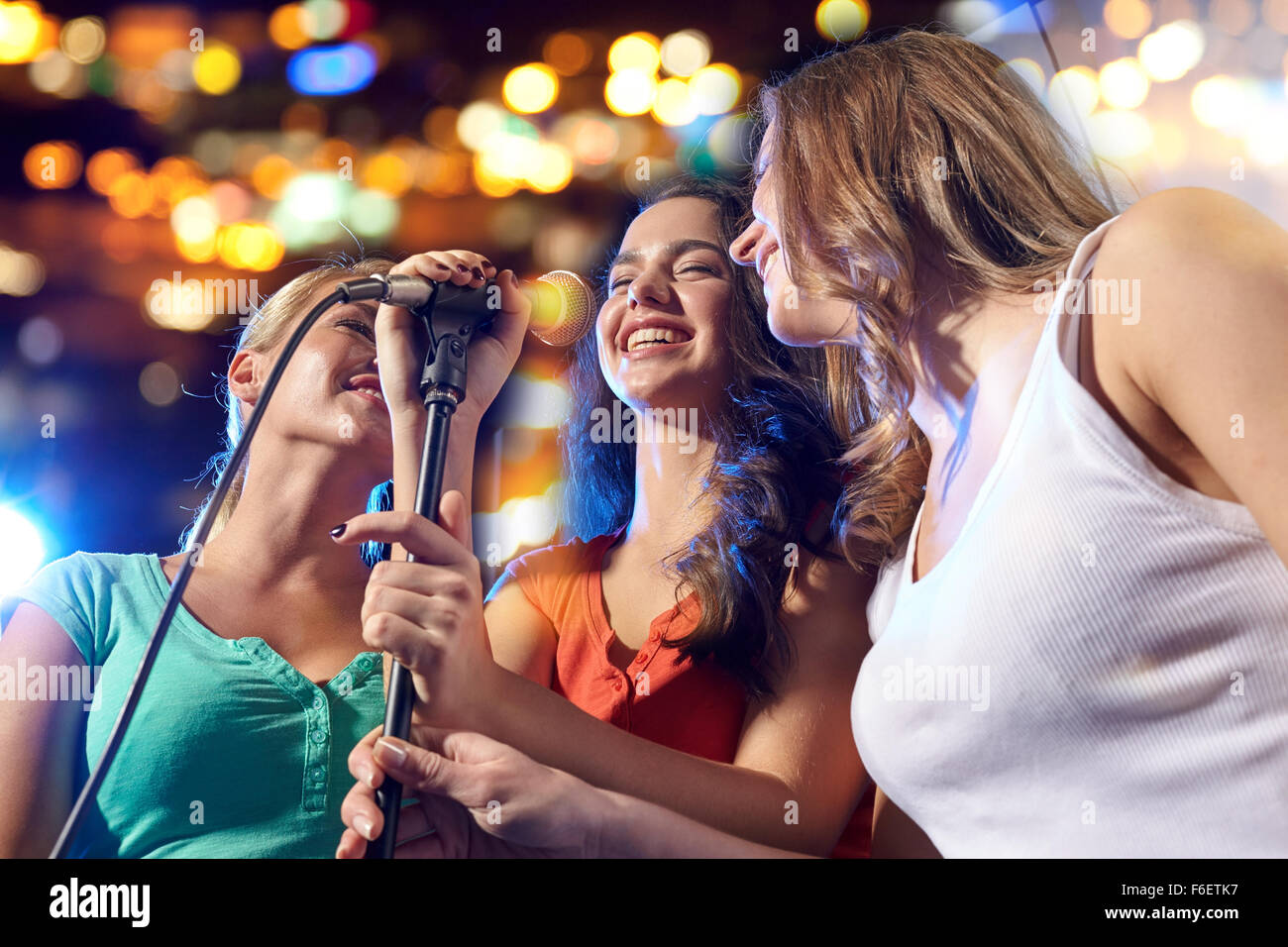 Happy young women singing karaoke dans night club Banque D'Images