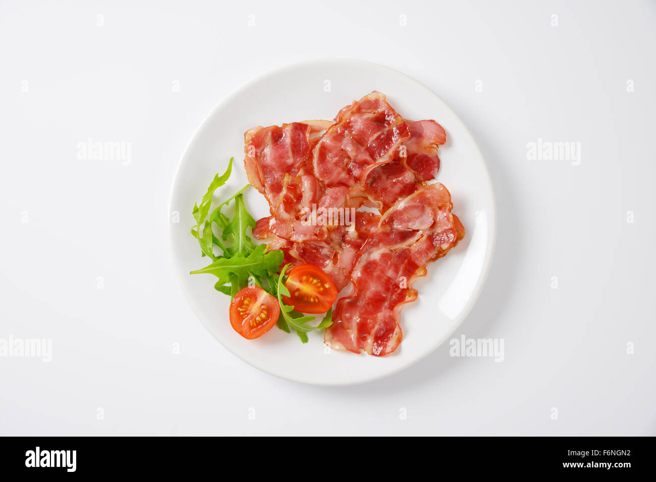 Assiette de tranches de bacon frit avec garnir sur fond blanc Banque D'Images