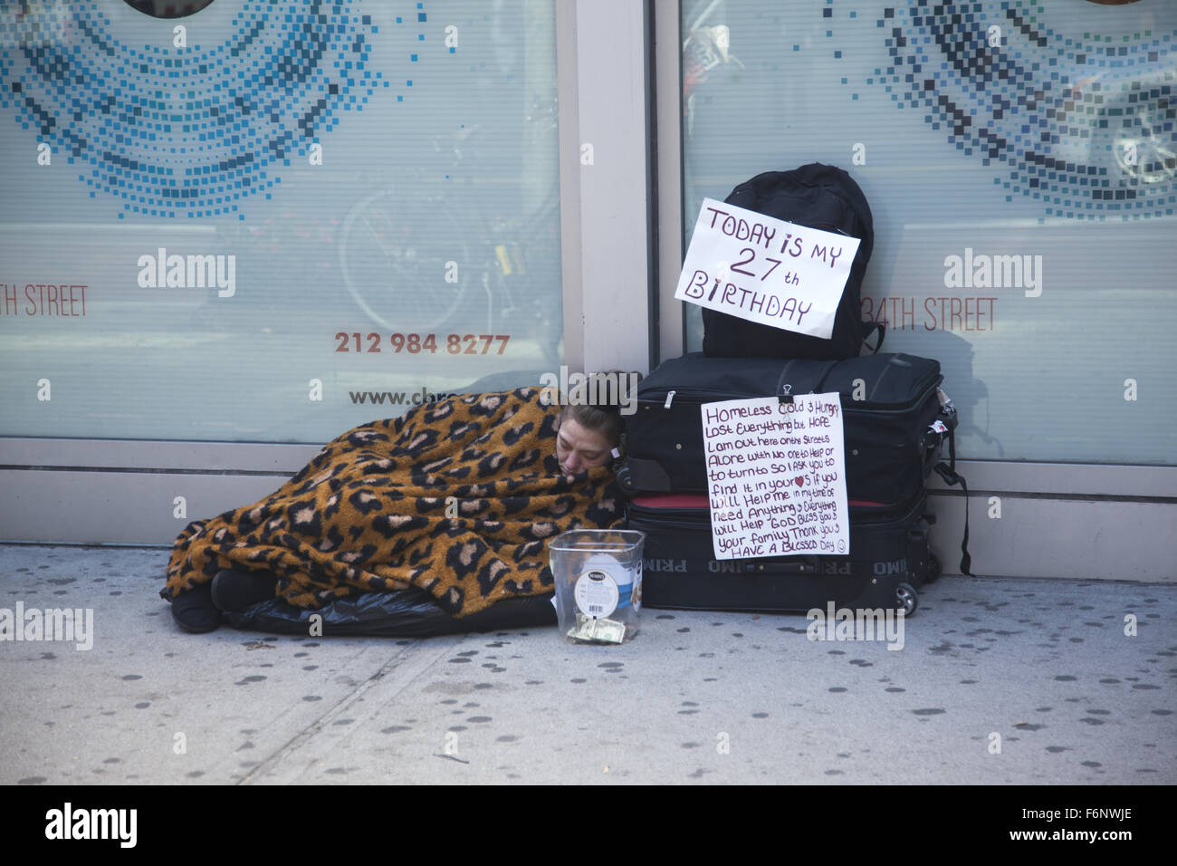 Femme sans-abri atteint à l'aide de son 27e anniversaire de dormir sur le trottoir sur 34th Street à Manhattan, New York. Banque D'Images
