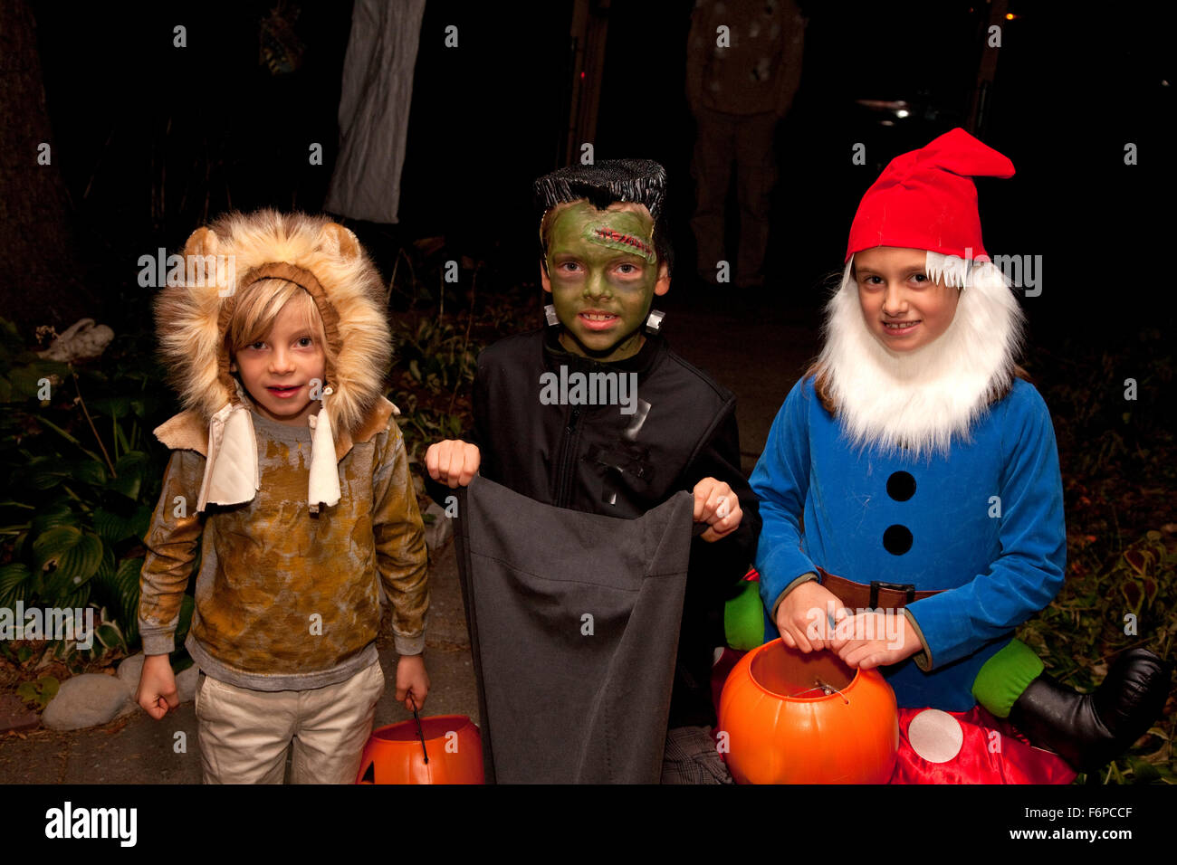 Trois enfants vêtus de leurs costumes de Halloween trick ou traiter. St Paul Minnesota MN USA Banque D'Images
