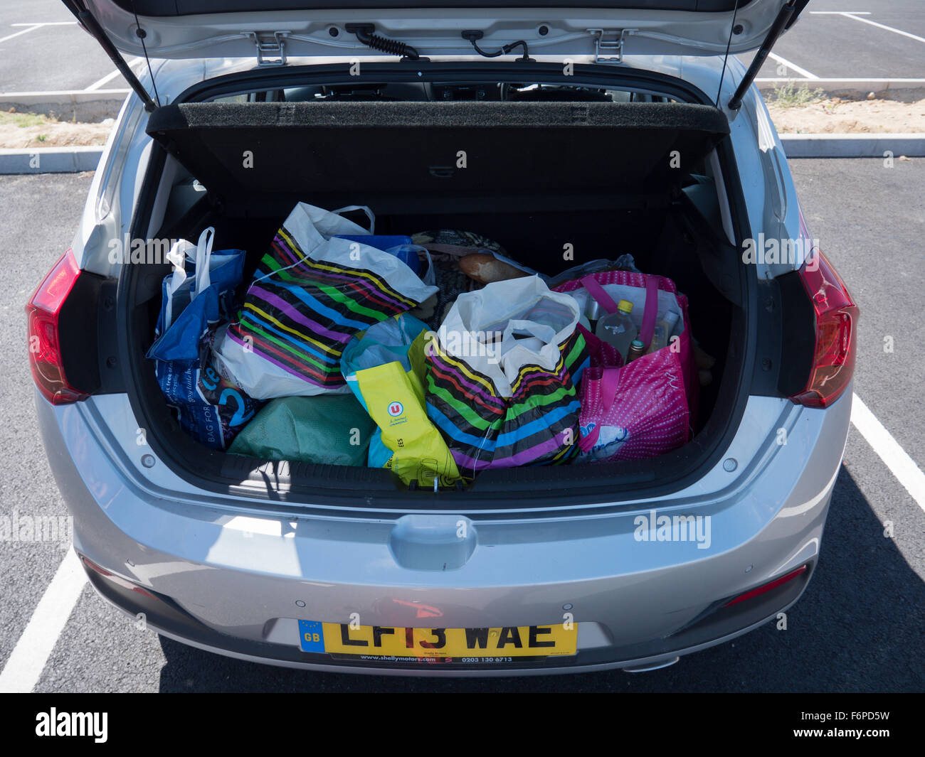 Le coffre d'une voiture remplie de sacs de magasinage en plastique coloré Banque D'Images