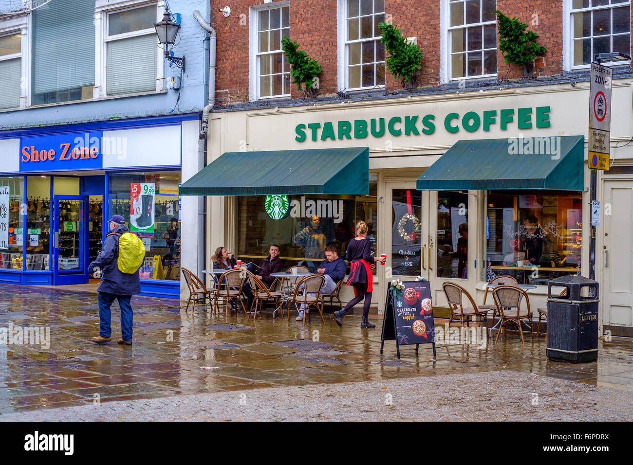 Les gens assis à l'extérieur de l'entreprise Starbucks coffee shop un jour de pluie à Salisbury Wiltshire, Royaume-Uni Banque D'Images