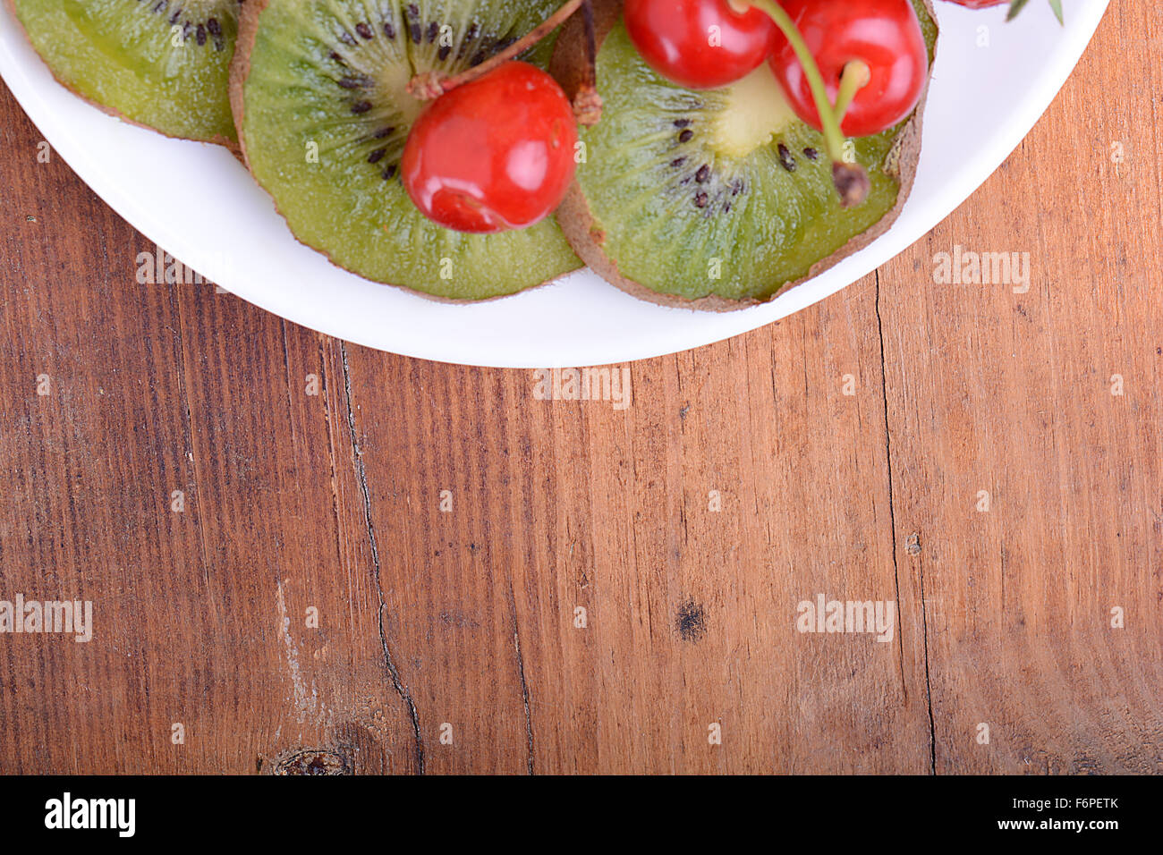 Fruits santé avec cerise, tranches de kiwi sur plaque de bois Banque D'Images