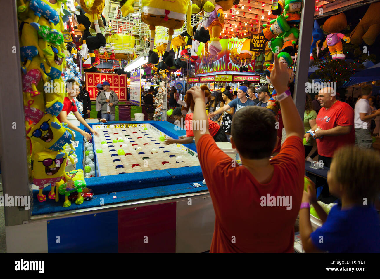 Un enfant soulève ses bras après avoir gagné au jeu "pas de gobelet'. Exposition nationale canadienne (CNE), Toronto, Ontario, Canada. Banque D'Images