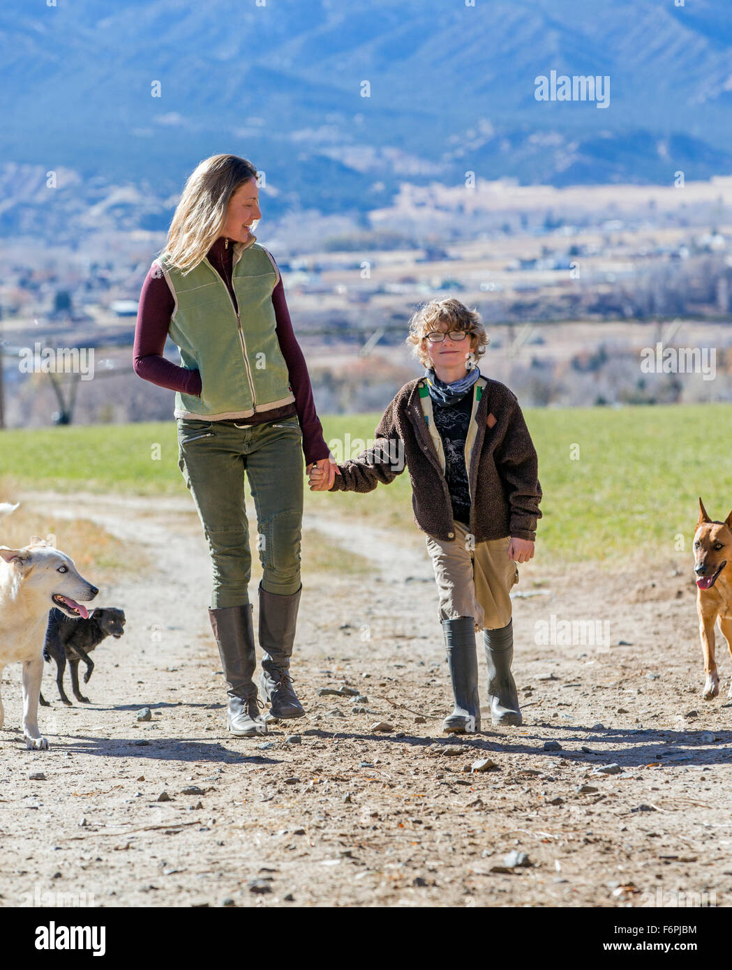 Belle Mère, jeune fils et des chiens de marcher le long chemin de terre sur ranch Banque D'Images
