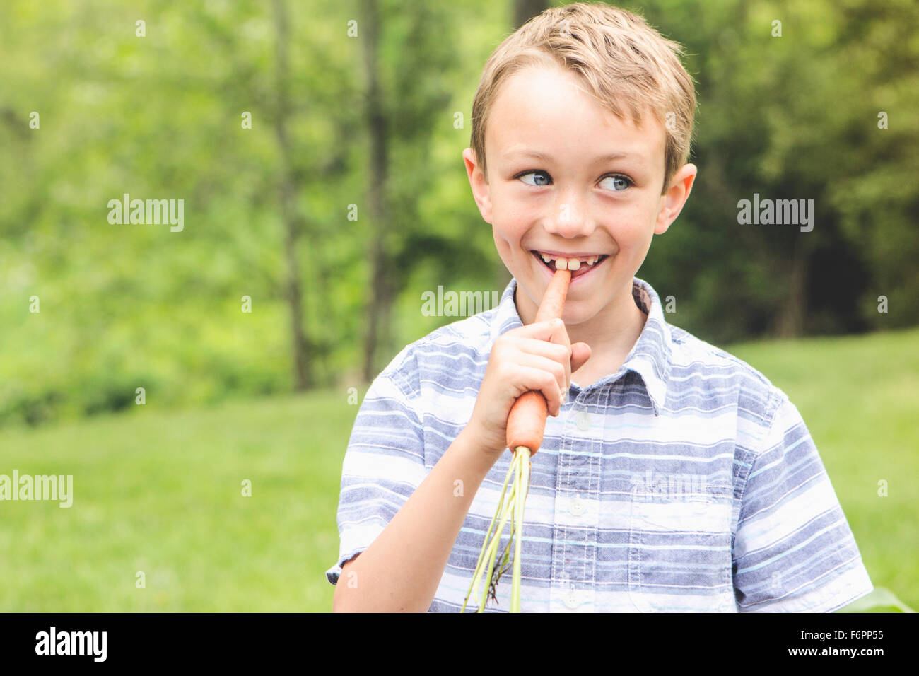 Caucasian boy eating carrot outdoors Banque D'Images