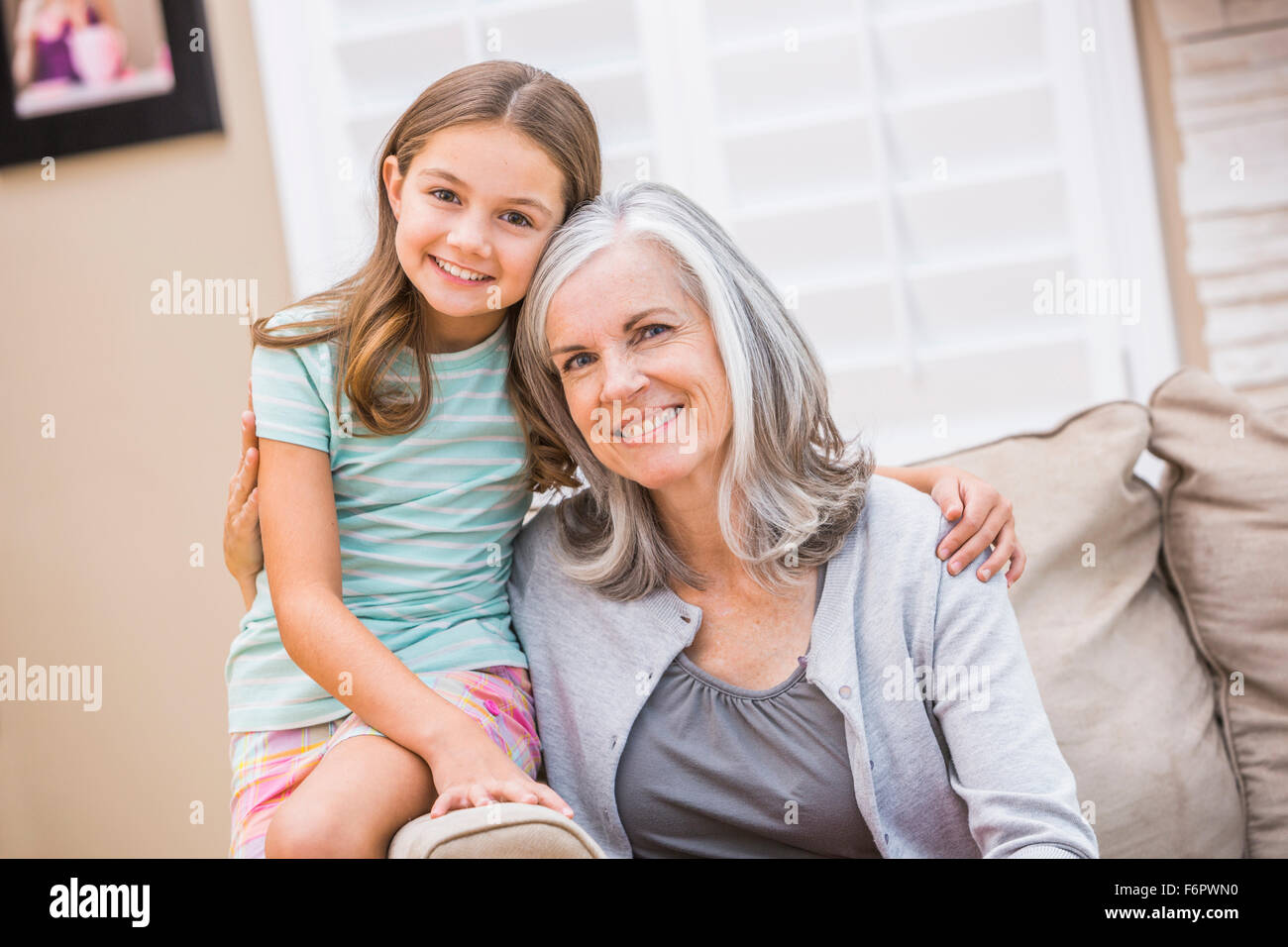 Grand-mère de race blanche et granddaughter hugging on sofa Banque D'Images