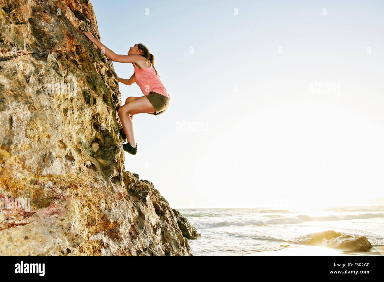 Woman climbing rock formation Banque D'Images