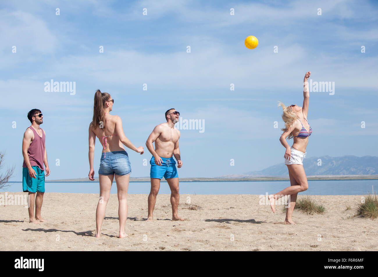 Groupe d'amis à jouer au volleyball de plage Banque D'Images