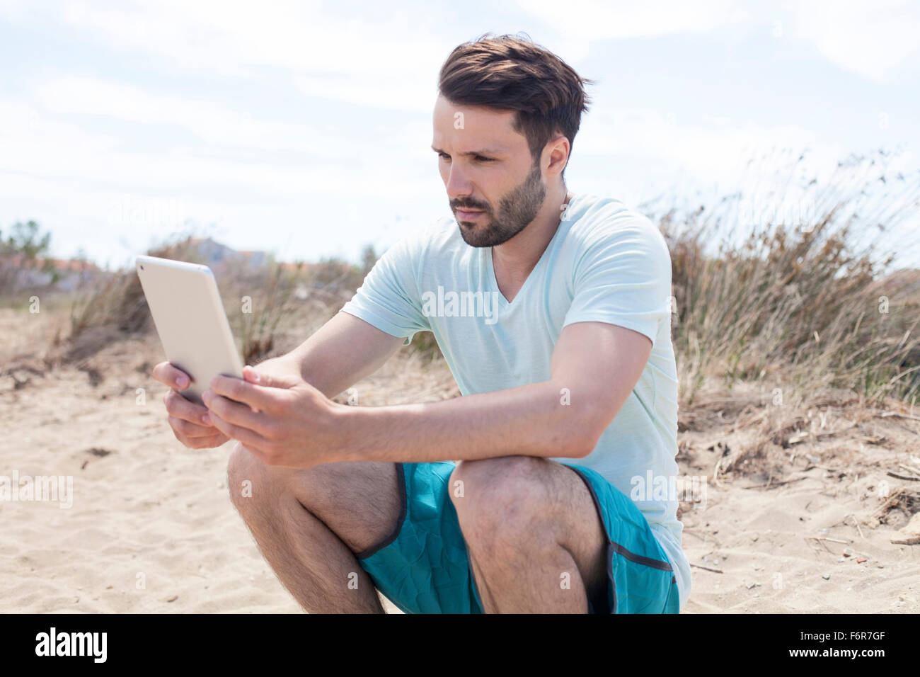Young man using digital tablet on beach Banque D'Images