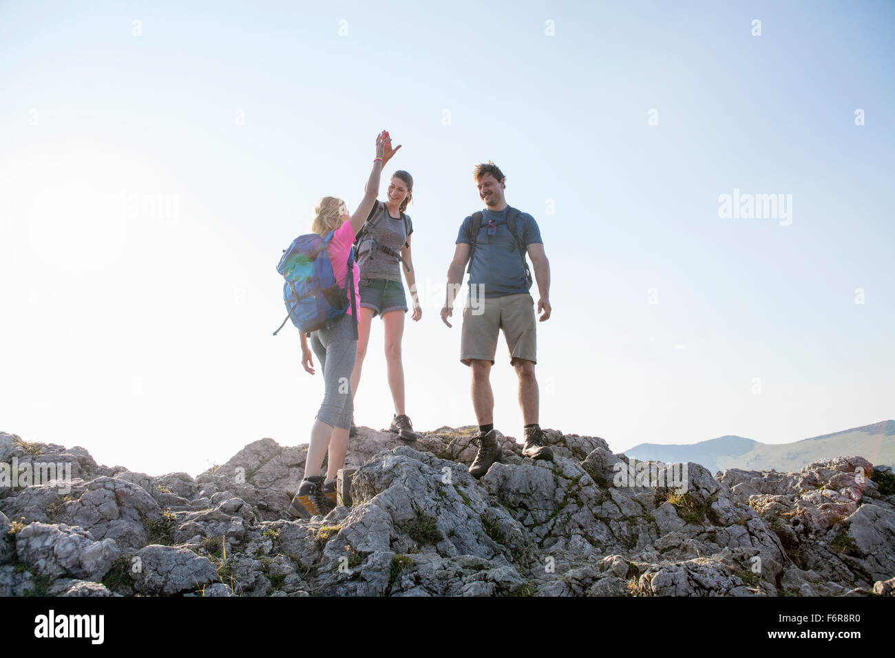 Groupe d'amis, offrant un rapport-cinq dans paysage de montagnes Banque D'Images