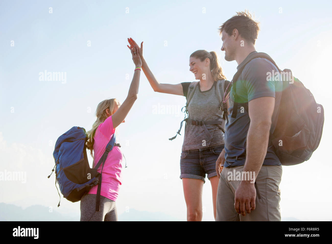 Groupe d'amis, offrant un rapport-cinq dans paysage de montagnes Banque D'Images