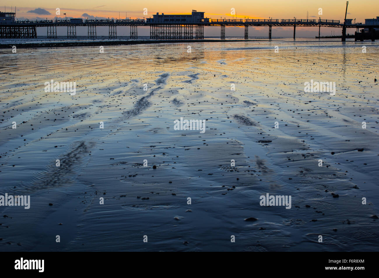 Les patrons du sable, de la jetée et du coucher du soleil à marée basse à Worthing Banque D'Images