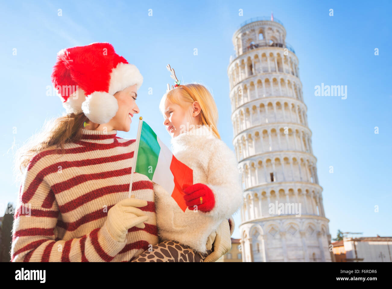 Happy mother in Christmas hat and daughter wearing reindeer antlers