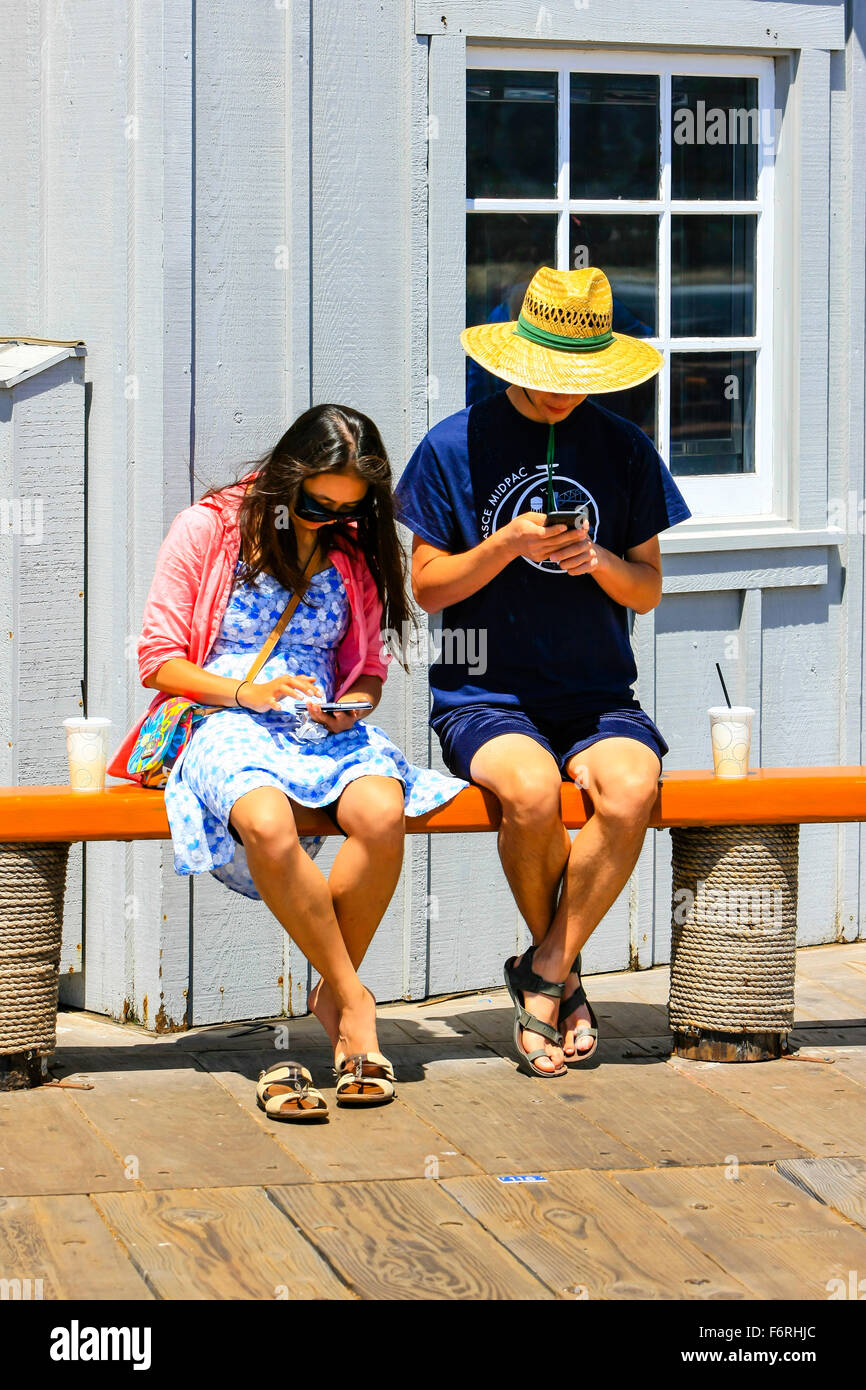 Deux personnes assis sur une banquette en interaction avec leur cellulaire mais ignorer les uns les autres Banque D'Images