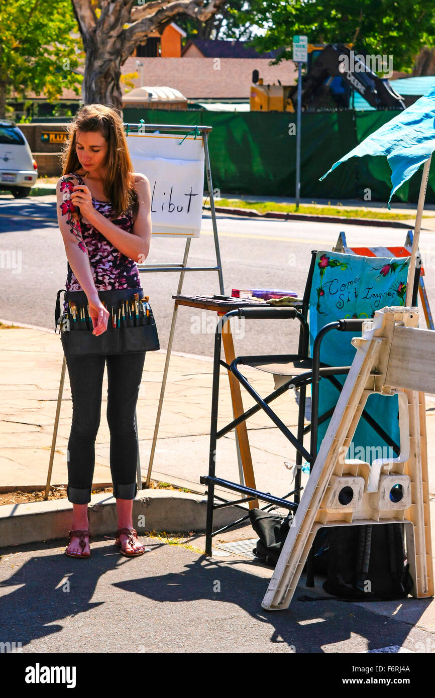 Jeune artiste de peinture de carrosserie au marché de fermiers à Santa Barbara en Californie attendant son prochain client désirant un ta peint à la main Banque D'Images