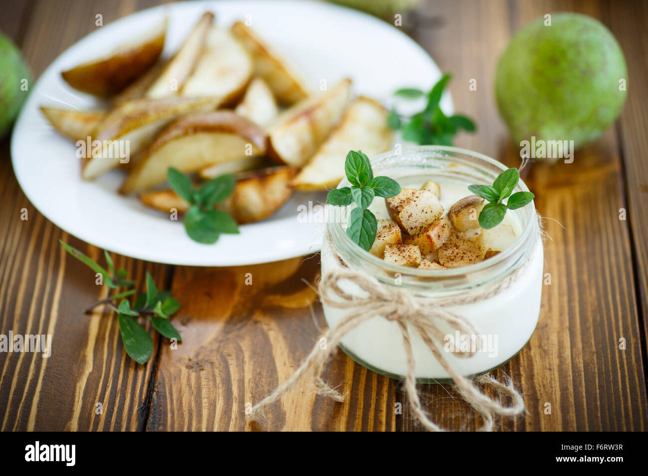 Le yaourt avec les poires rôties dans un bocal en verre Banque D'Images