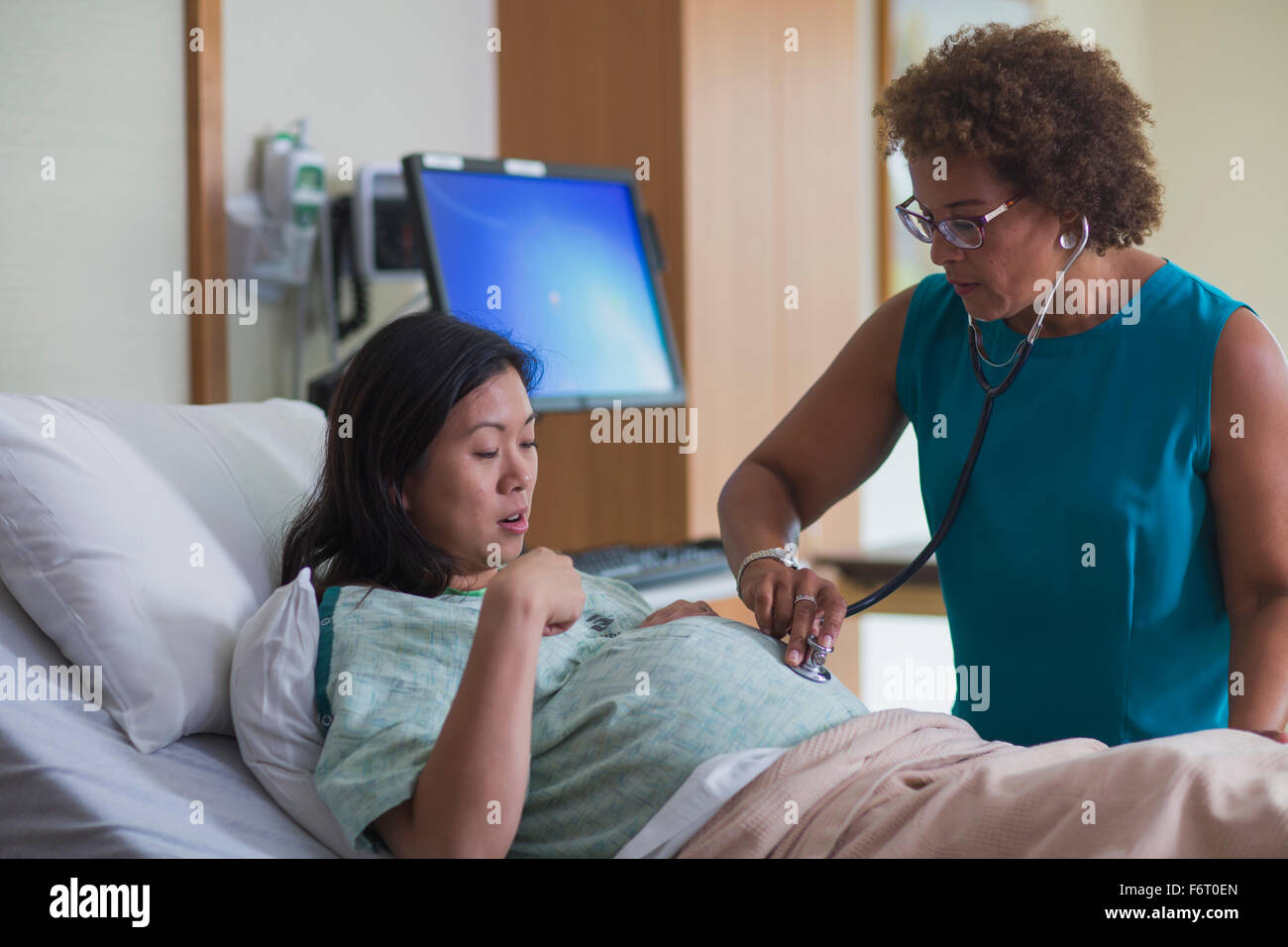 Médecin à l'écoute de ventre de la patiente enceinte Banque D'Images