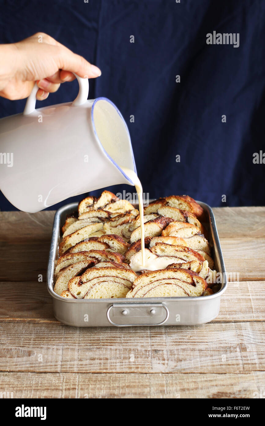 Préparer le pudding.Verser ce mélange sur les tranches de pain brioché dans une casserole Banque D'Images