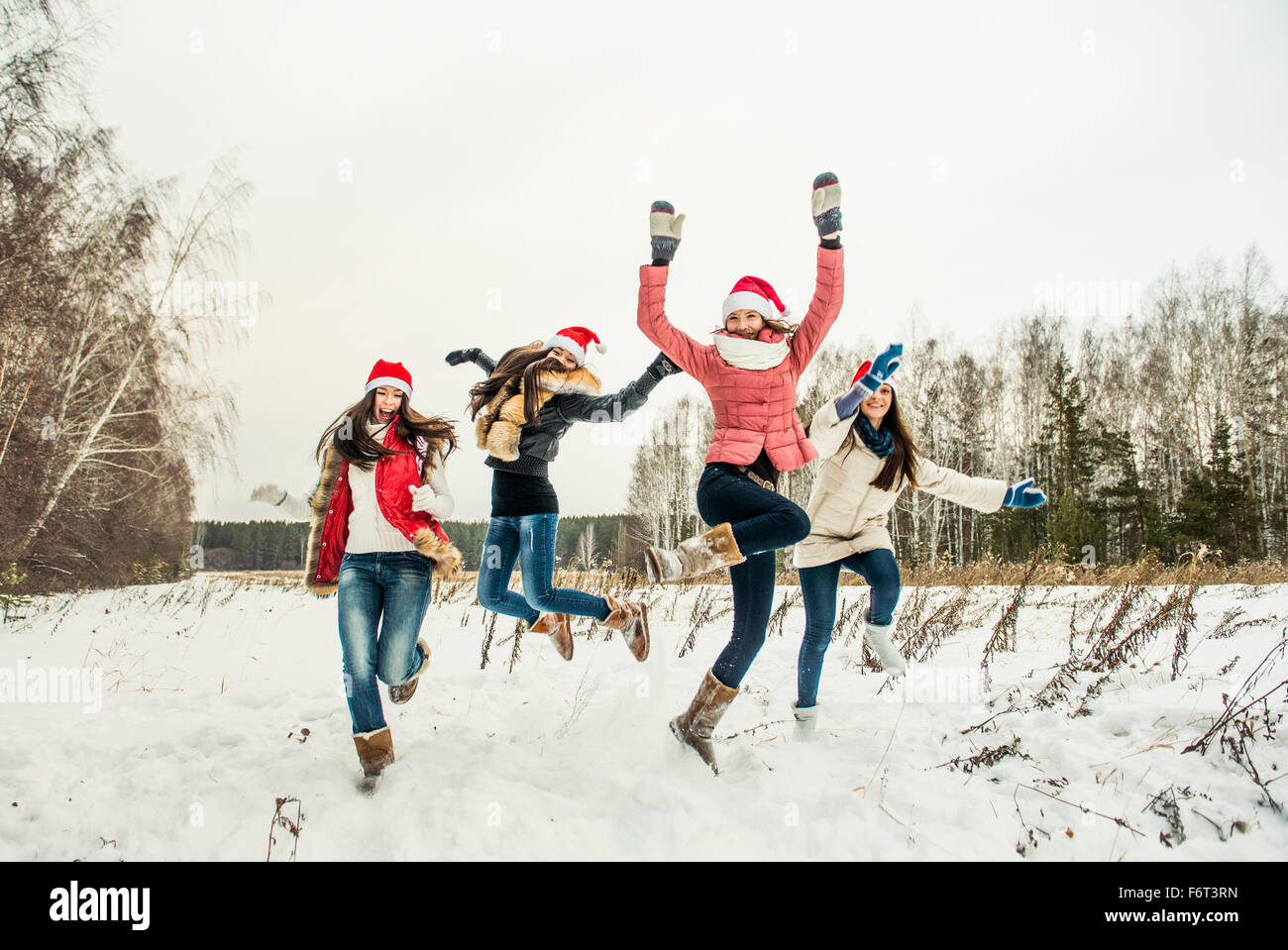 Filles caucasiennes sauter de joie dans la neige Banque D'Images