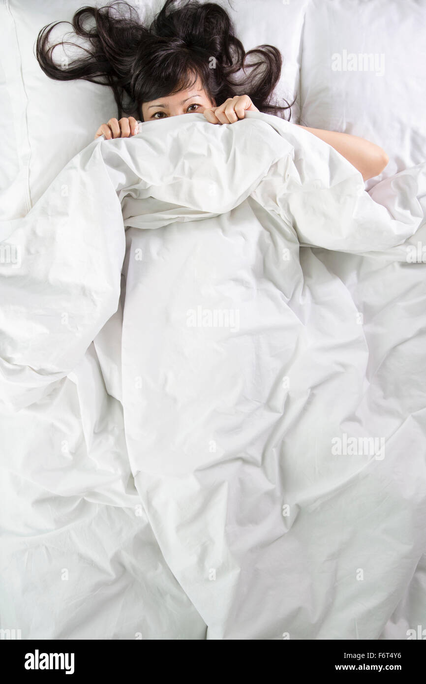 Mixed Race woman, à des couvertures de lit Banque D'Images