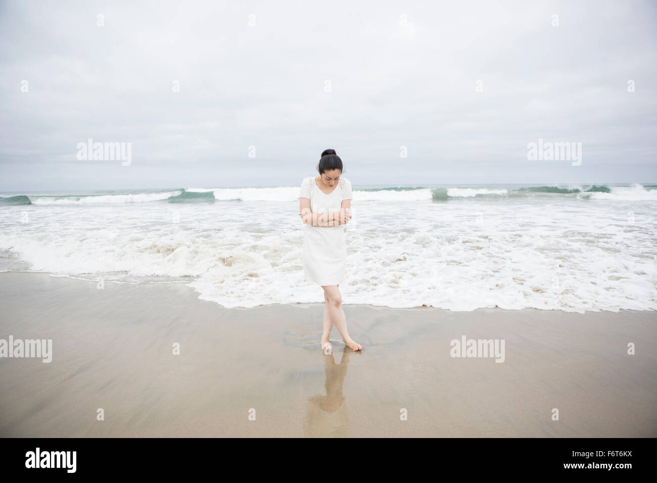 Femme debout près de vagues sur la plage Banque D'Images