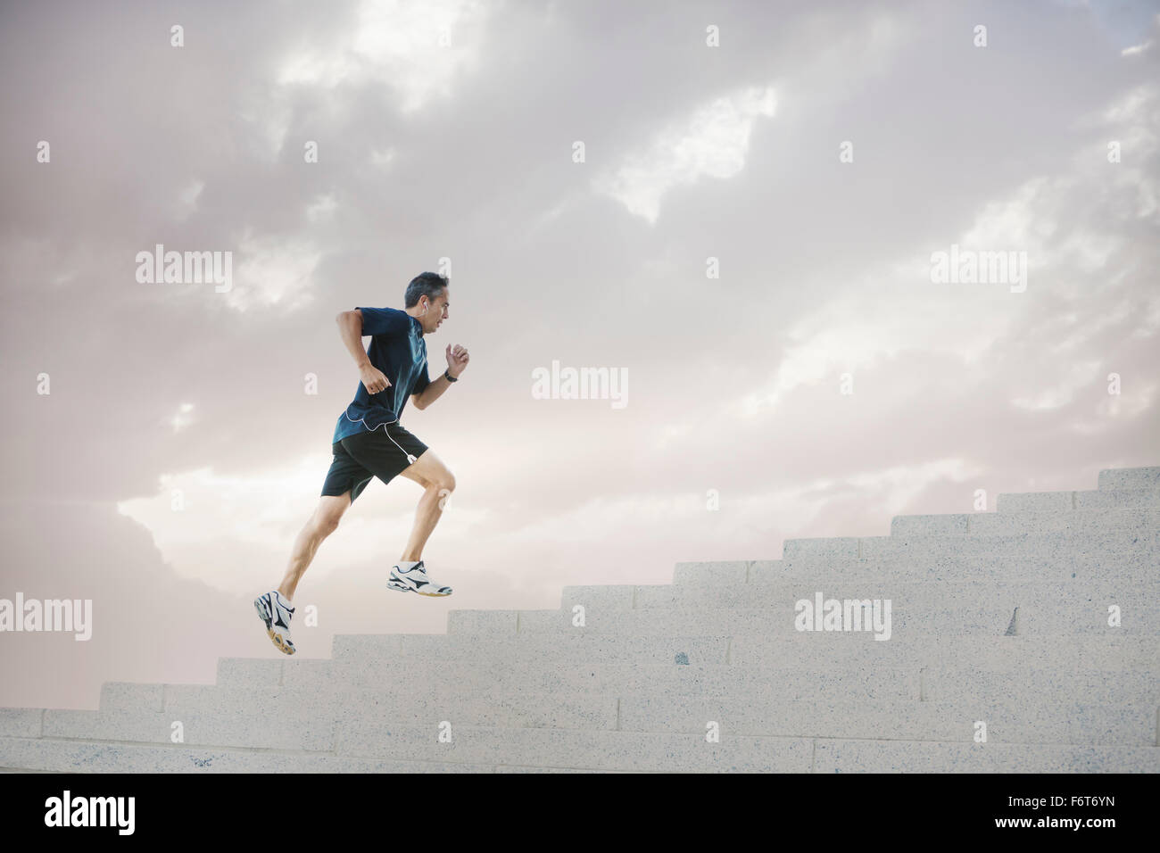 Mixed Race man jogging on steps Banque D'Images