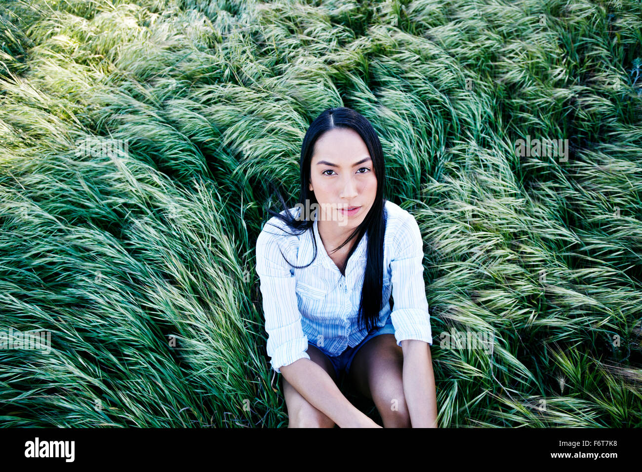 Mixed Race woman sitting in grass Banque D'Images