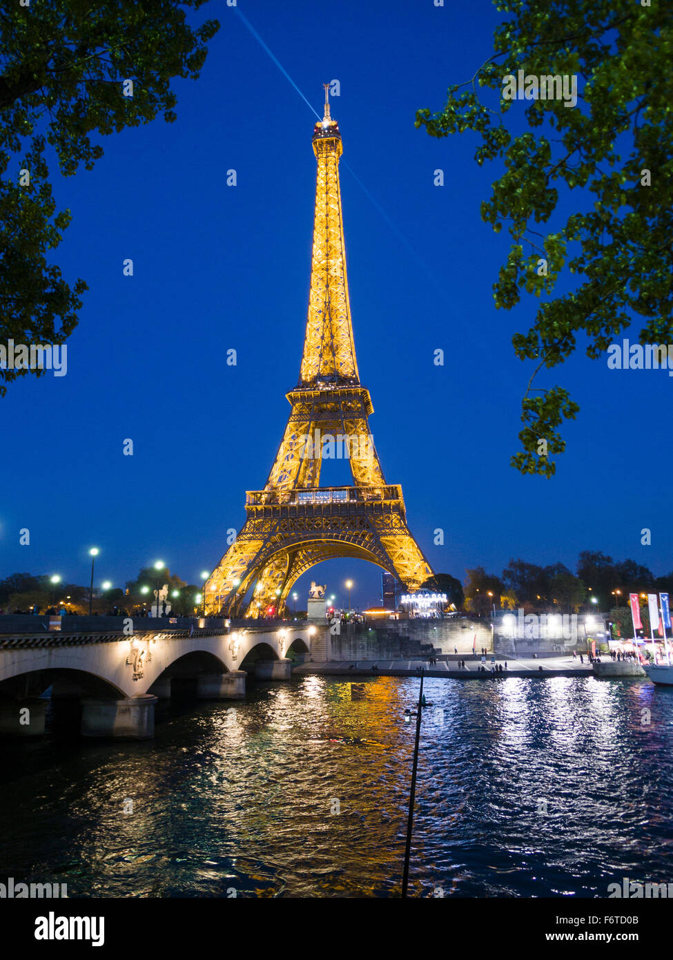 La Tour Eiffel éclairée au crépuscule et se reflétant dans la Seine. Un projecteur éclaire par le haut. Paris, Île-de-France, France Banque D'Images