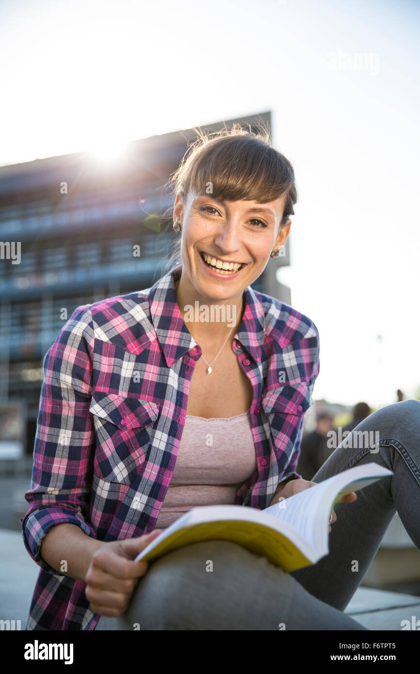 Portrait of smiling young woman with book au crépuscule Banque D'Images