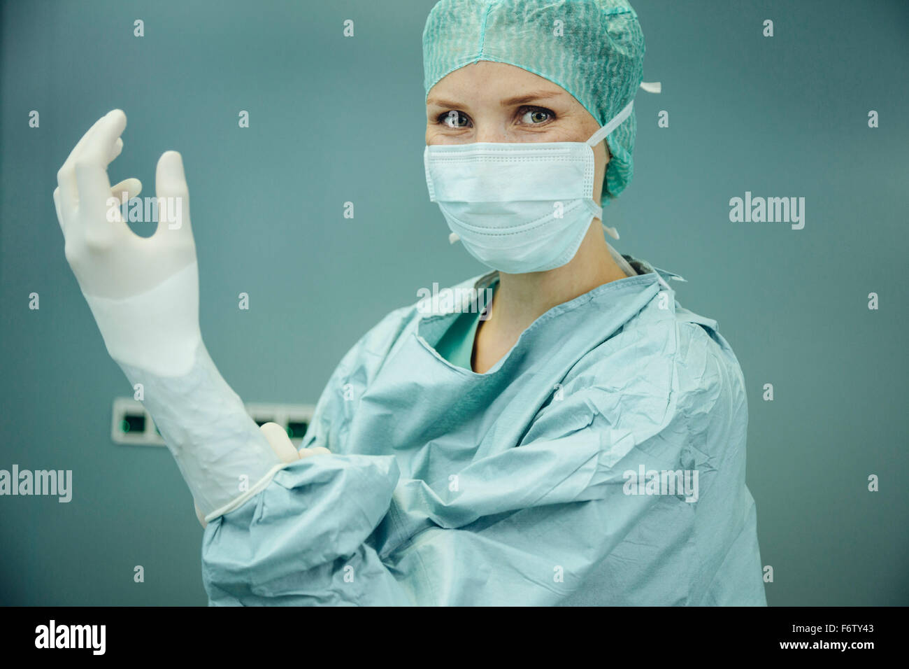 Chirurgienne de mettre des gants chirurgicaux Banque D'Images