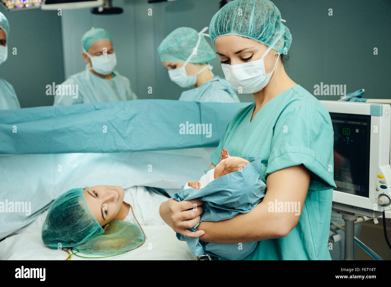 L'infirmière de salle d'opération montrant nouveau-né à mère Banque D'Images