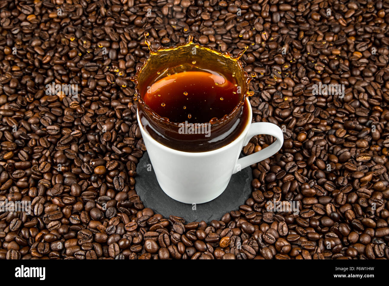 Tasse de café splash sur les grains de café Banque D'Images