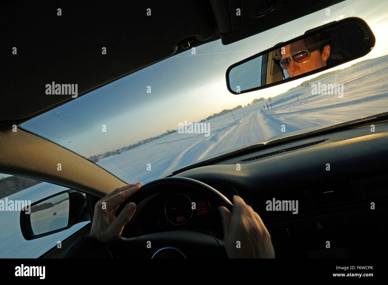 L'homme conduisant une voiture le long d'une rue couverte de neige, Bavière, Allemagne Banque D'Images