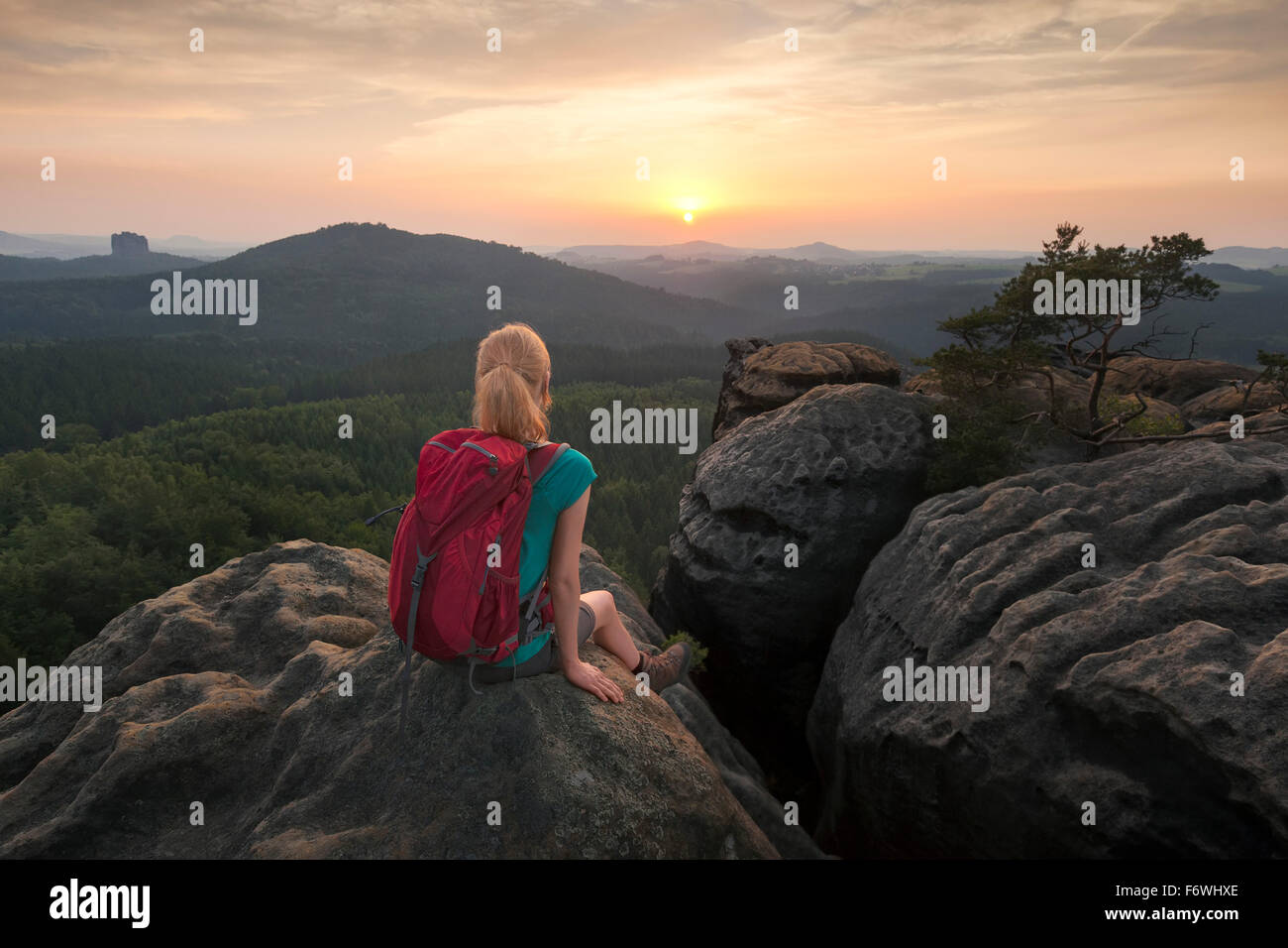 Jeune femme assise sur un rocher tout en admirant le coucher du soleil, Parc National de la Suisse Saxonne, Saxe, Allemagne Banque D'Images