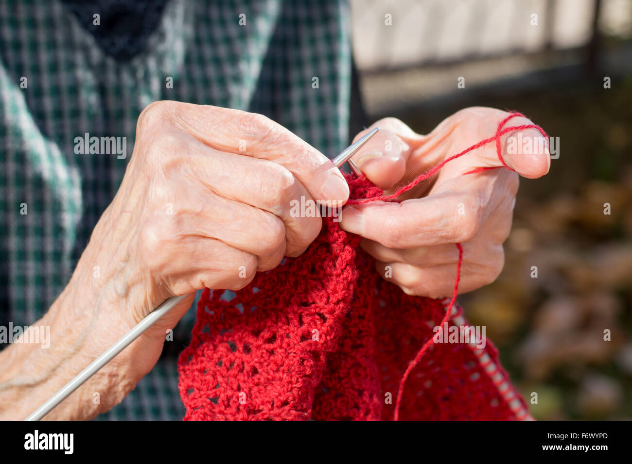 Vieille Femme mains tricotant une chandail rouge pour un cadeau de Noël Banque D'Images