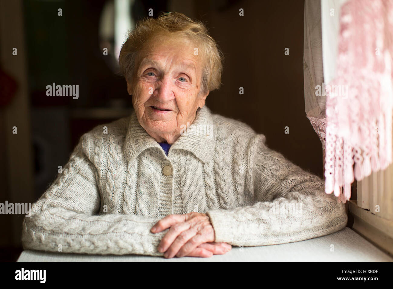 Portrait d'une vieille femme assise dans une maison de village. Banque D'Images
