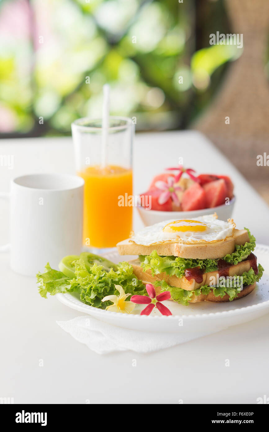 Petit-déjeuner sain avec jeu de sandwich œuf et salade de fruits ainsi que du café et du jus d'orange Banque D'Images