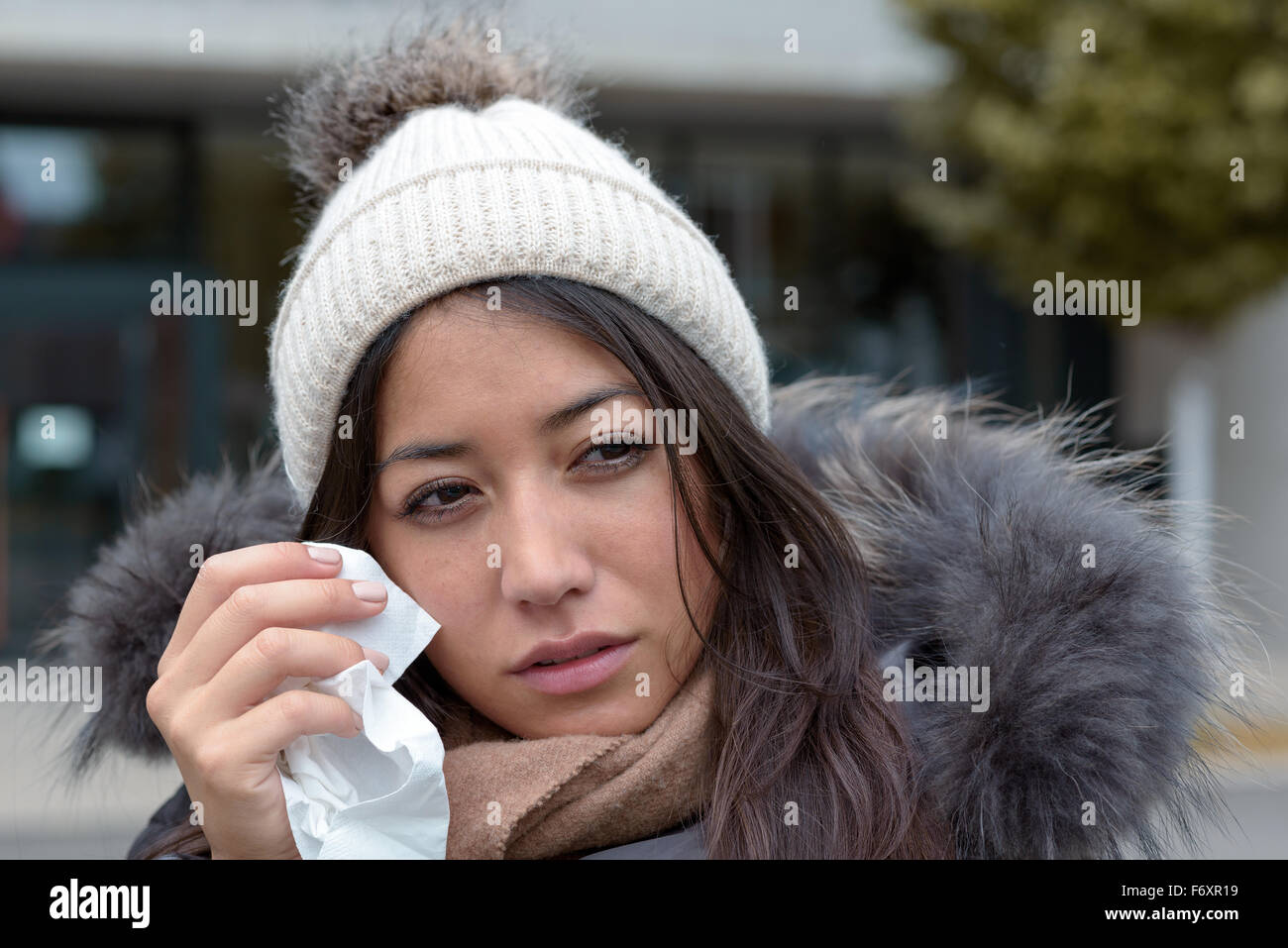 Femme en larmes triste mode hiver chaud en tenant un mouchoir à son visage pour sécher les larmes de ses yeux regardant à droite Banque D'Images