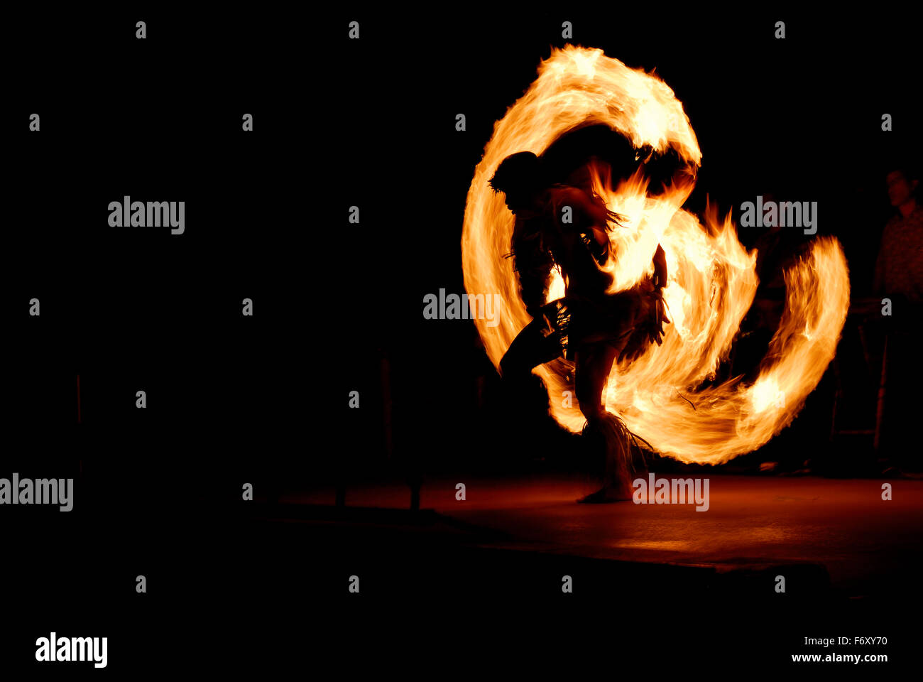 Silhouette of Native Hawaiian fire dancer spinning matraques en flammes dans la nuit après un luau Maui Hawaii Banque D'Images