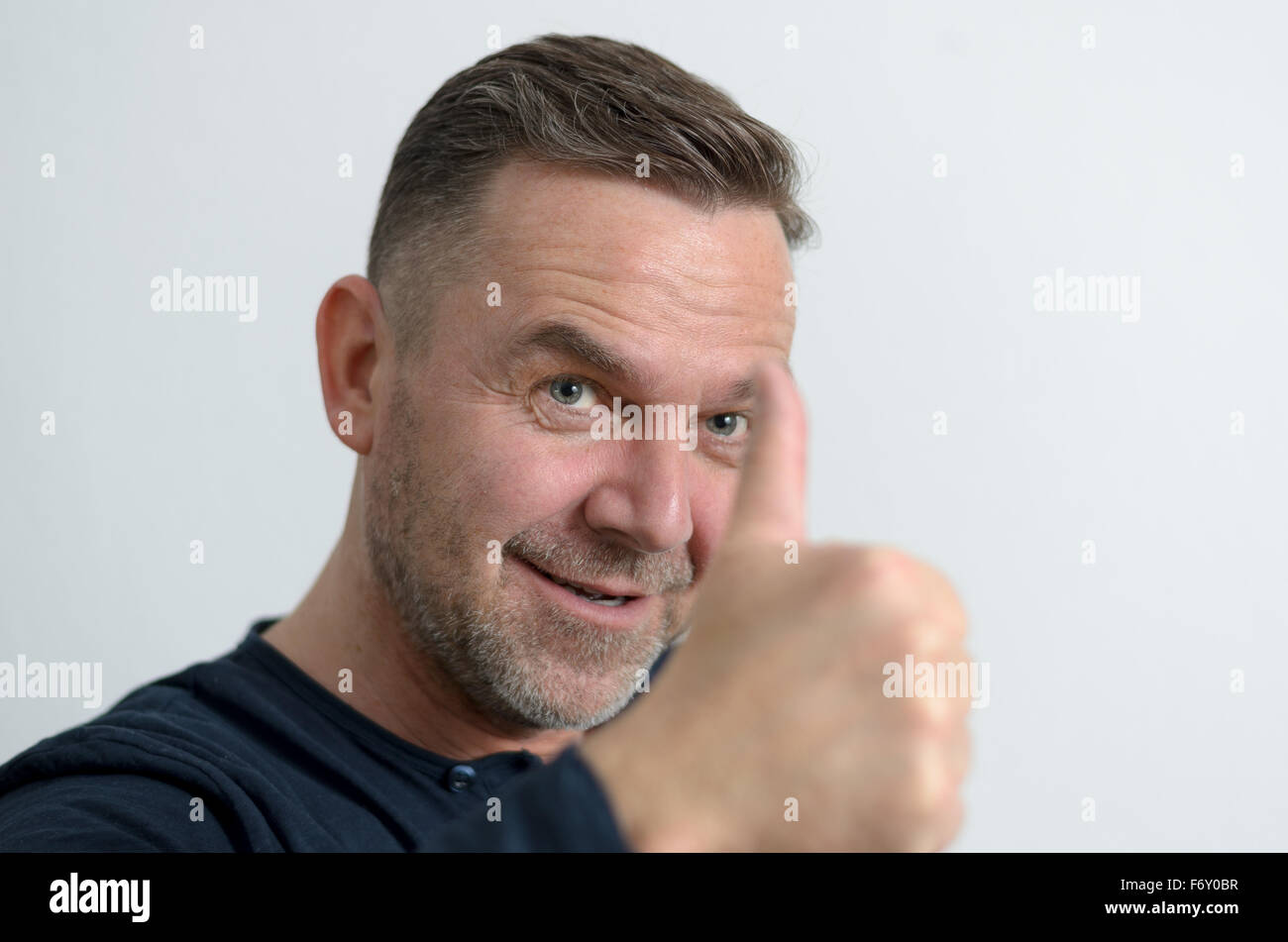 Blue Eyed homme d'âge moyen avec une attitude positive woman showing thumb up, portrait avec copie espace sur gris Banque D'Images