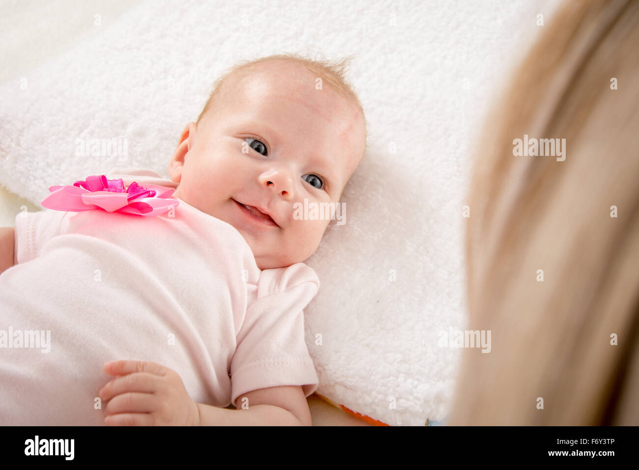 Deux Mois D Un Bebe Couche Sur Le Dos Sur Le Lit Assis A Cote De L Enfant Et Sa Mere La Regardant Photo Stock Alamy