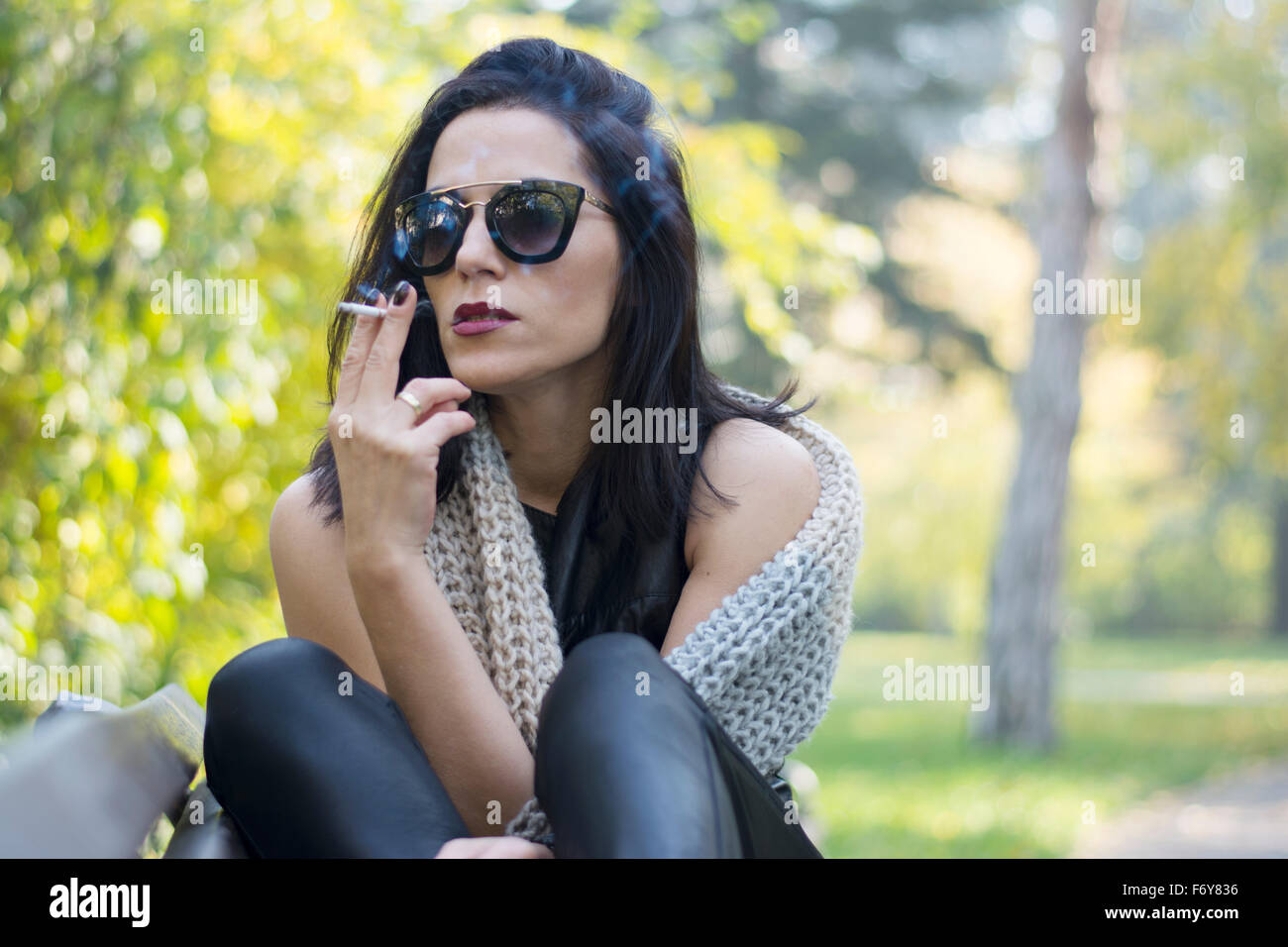 Belle black hair woman enjoying cigarette dans park Banque D'Images