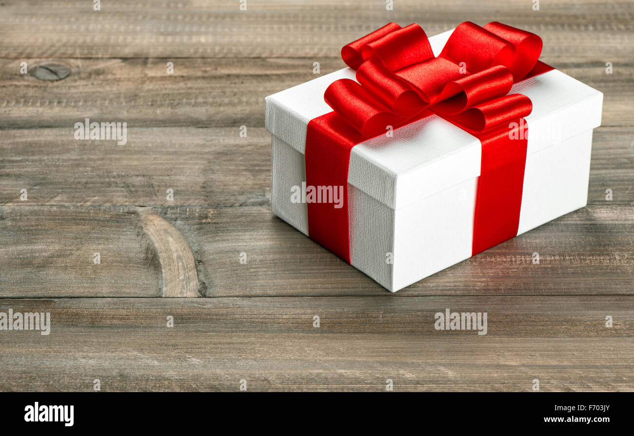 Boîte-cadeau avec ruban rouge noeud sur fond de bois. Décoration de vacances Banque D'Images
