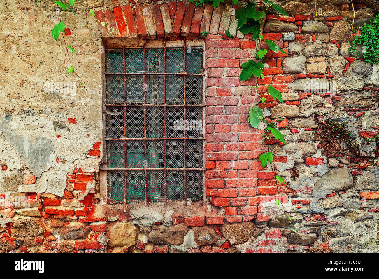 Fragment de l'ancienne maison de brique avec fenêtre fermée derrière des barres de fer dans la petite ville italienne du Piémont, Italie du Nord. Banque D'Images